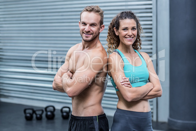 Smiling muscular couple giving back to back