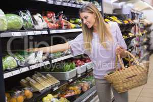 Smiling woman taking a vegetables in the aisle