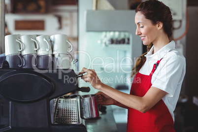 Pretty barista using the coffee machine