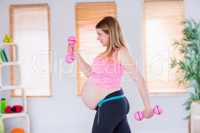 A pregnant woman holding dumbbells