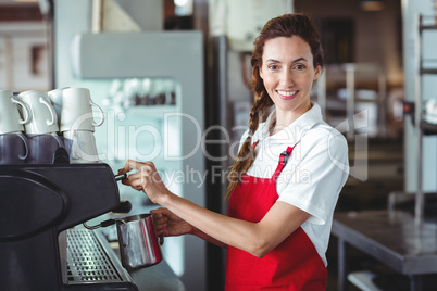 Pretty barista looking at camera and using the coffee machine