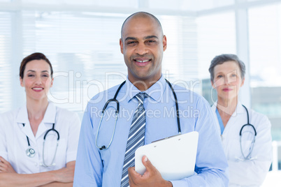 Portrait of smiling doctor holding file and standing in front of