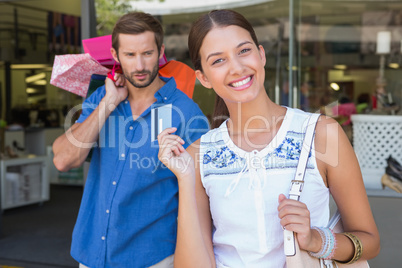 Young happy woman with a concerned man holding shopping bags beh
