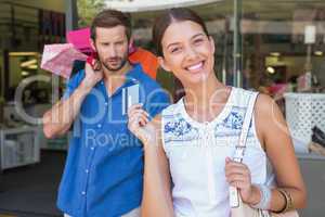 Young happy woman with a concerned man holding shopping bags beh