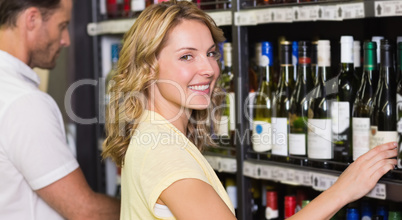 Portrait of smiling pretty woman buying a wine bottle