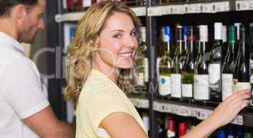 Portrait of smiling pretty woman buying a wine bottle