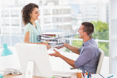 Businesswoman giving a stack of folders to her colleague