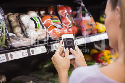 Woman reading her shopping list on smartphone