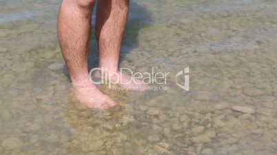Man is cooling his feet in a lake