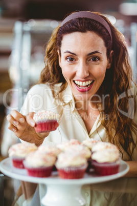 Pretty brunette smiling at camera and holding cake