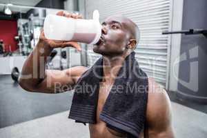 Young Bodybuilder drinking a bottle of water after the training