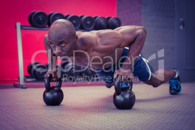 Muscular man doing push-ups with kettlebells