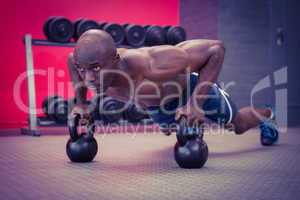 Muscular man doing push-ups with kettlebells