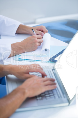 Medical colleagues working with laptop and taking notes