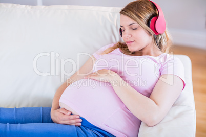 Pregnant woman listening music and touching her belly