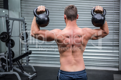 Muscular man lifting two kettlebells