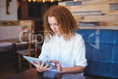 Pretty girl using a small tablet at table