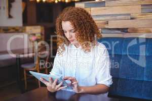 Pretty girl using a small tablet at table