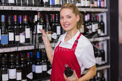 Portrait of a smiling blonde worker taking a wine bottle