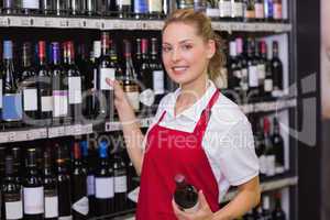 Portrait of a smiling blonde worker taking a wine bottle