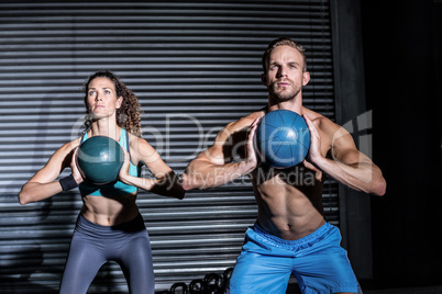 Muscular couple doing ball exercise