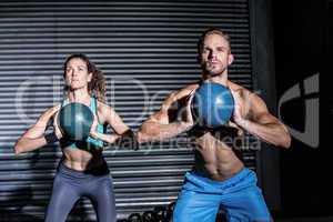 Muscular couple doing ball exercise