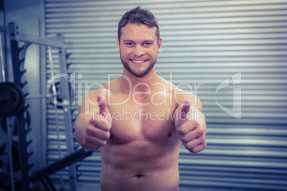 Portrait of smiling muscular man looking at camera with thumb up