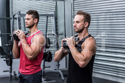 Muscular men exercising with kettlebells