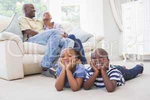 Happy siblings sitting on the floor watching television