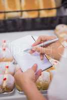 a woman  taking notes above pastries
