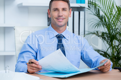 Smiling businessman reading a contrat before signing it