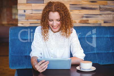 Pretty girl using a small tablet at table