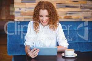 Pretty girl using a small tablet at table