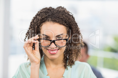 Pretty businesswoman tilting her reading glasses