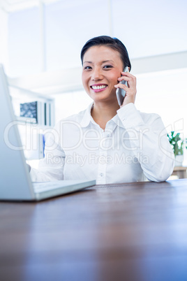 Businesswoman having phone call and using laptop computer
