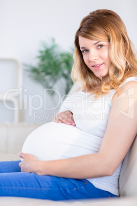 Pregnant woman looking at camera with hands on belly