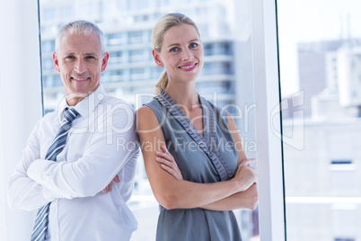 Two business people smiling at the camera in the office