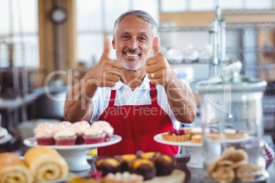 Happy barista looking at camera and gesturing thumbs up