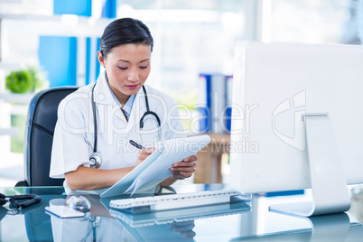Concentrated doctor writing on clipboard