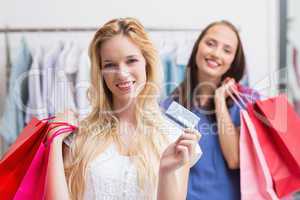 Happy friends holding a credit card