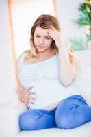 Pregnant woman having headache on couch