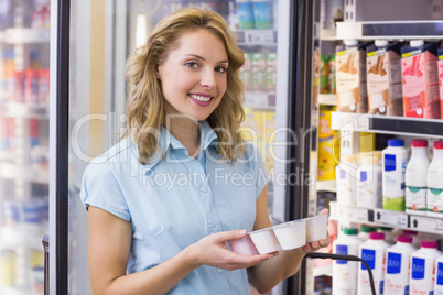 Portrait of a smiling woman having on her hands a fresh yogurt