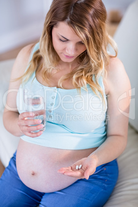 Pregnant woman taking a vitamin tablet