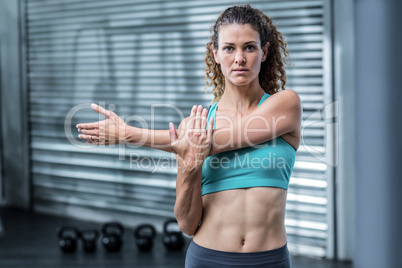 Attentive muscular woman stretching arms