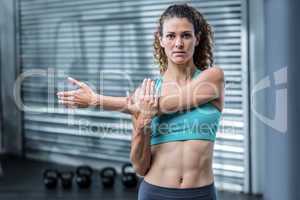 Attentive muscular woman stretching arms