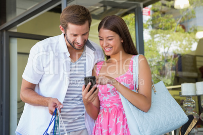 Happy couple smiling and looking at mobile phone