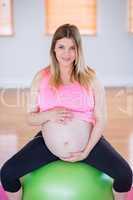 Pregnant woman touching her belly on exercise ball