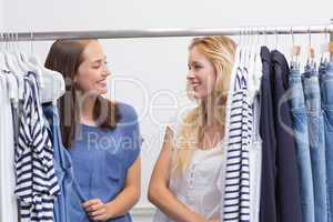 Happy friends browsing in the clothes rack