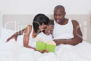 Pretty couple reading with his son in bed together