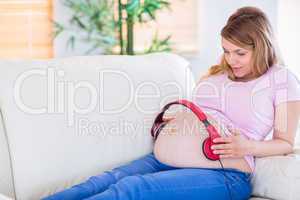 Pregnant woman putting headphones on her belly